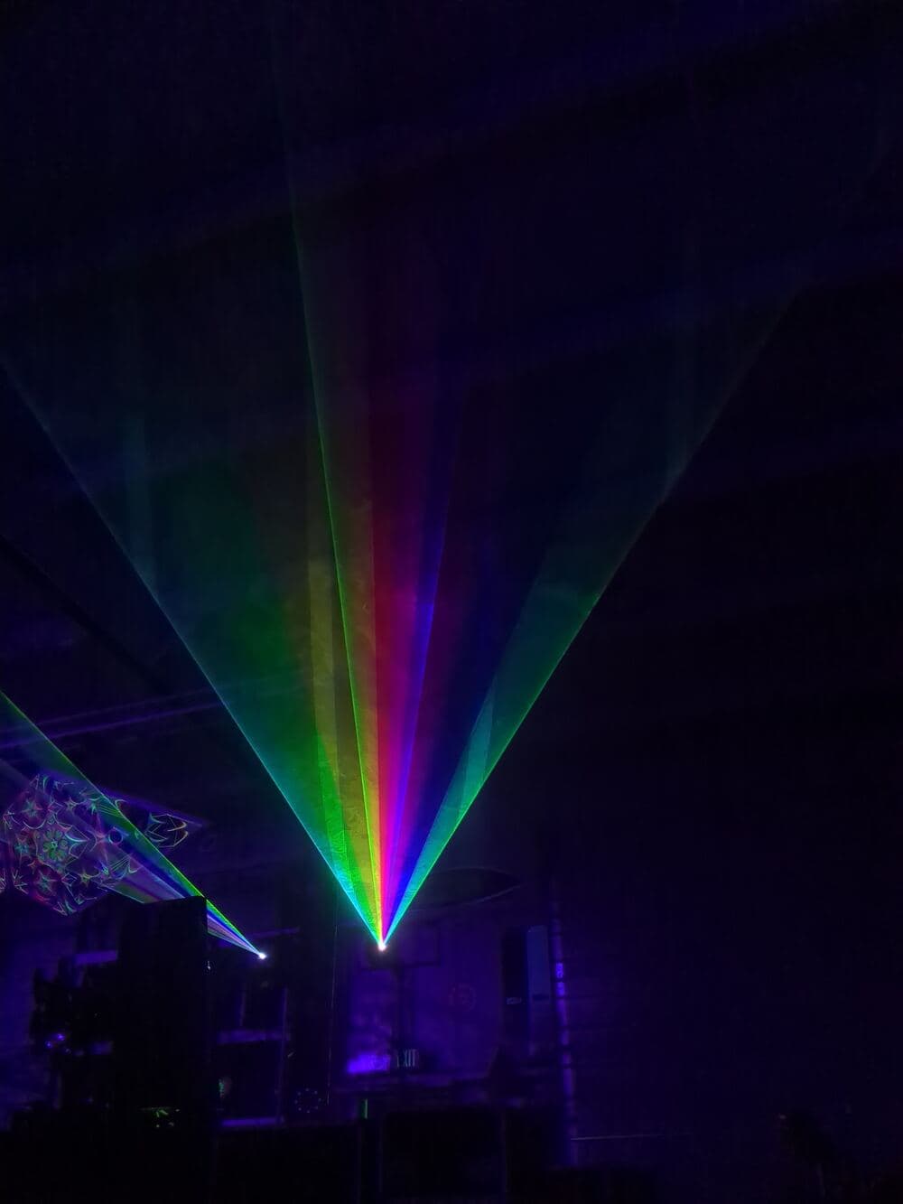 A fan of rainbow laser beams cutting through haze